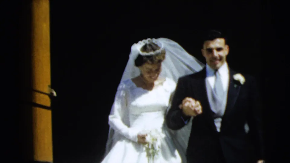 1962 Camden, New Jersey wedding footage showing a bride and groom leaving a church doorway hand in hand.