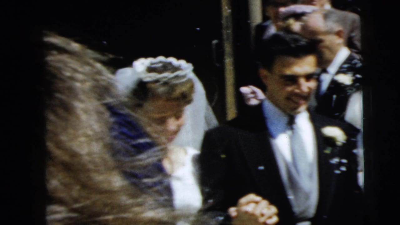 In 1962 Camden, New Jersey, a bride and groom appear to exit a church doorway while guests crowd around them.