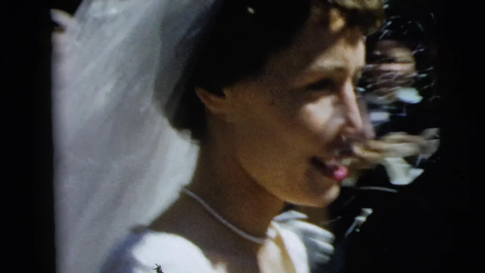 Close handheld view of the bride smiling during a 1962 Camden wedding exit as confetti or rice is tossed nearby.