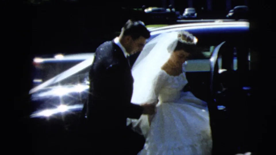 Home-movie view of the groom assisting the bride beside the wedding car in Camden, New Jersey, in 1962.