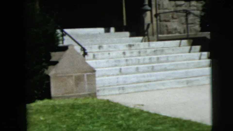 1962 Camden, New Jersey 8mm frame showing stone church steps, grass, railing, and masonry entrance details in bright daylight.