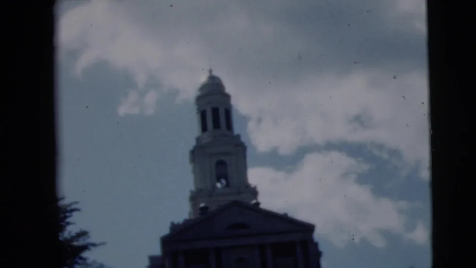 1962 Camden, New Jersey 8mm frame with a soft tilted view of the church tower, pediment, clouds, and dark tree edge.