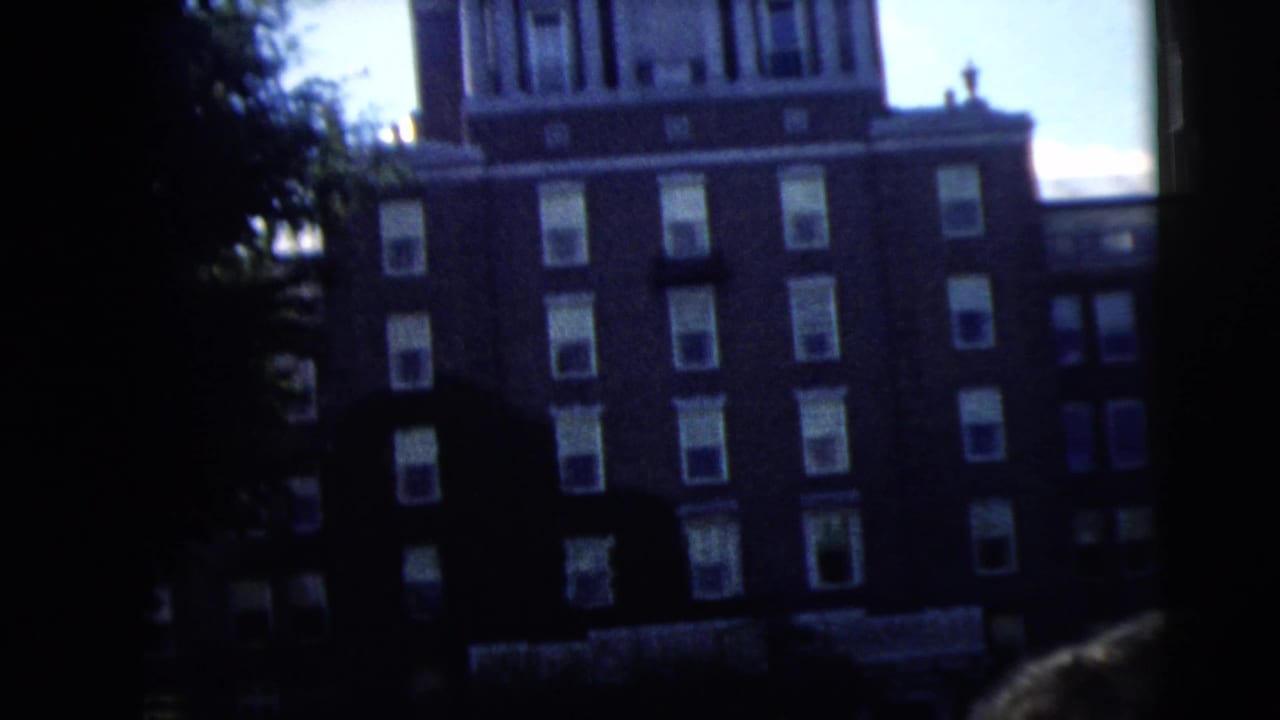 Dark residential or apartment building seen from a shaded street edge.