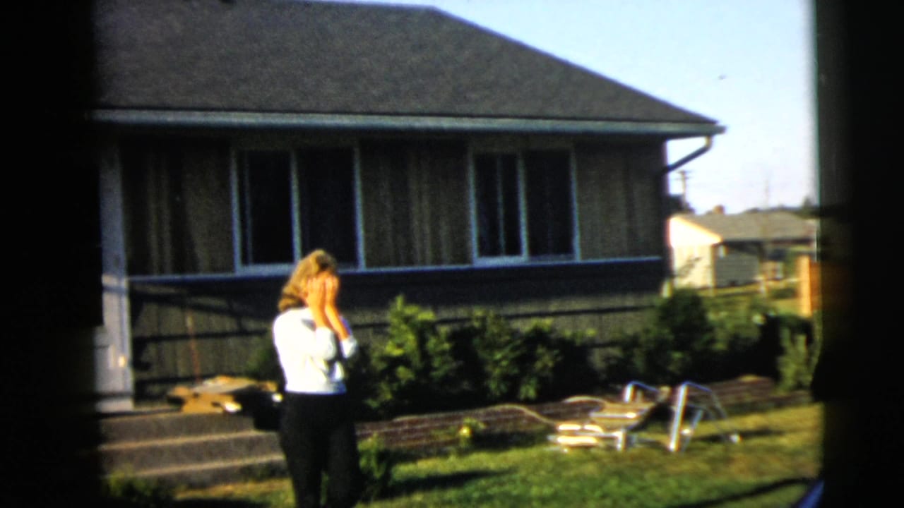Woman in a white blouse covers her face while standing in a sunny backyard.