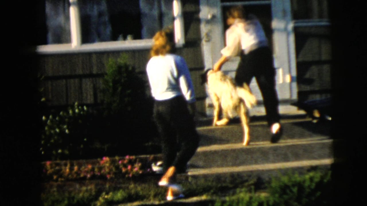 1962 Camden exterior frame with two women near a house entrance as one handles a large light-colored dog on the front steps.