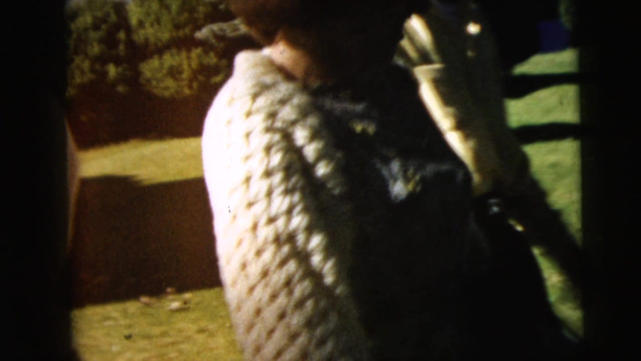 Close view of a person in a textured knit sweater outdoors on grass.