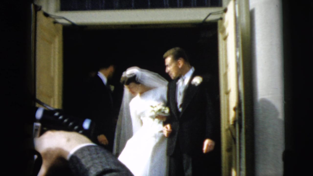 Bride and groom begin leaving a church doorway as a photographer leans in nearby.