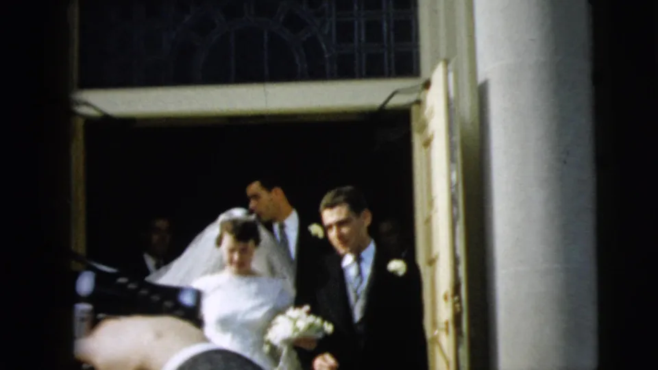 The couple emerges from the church entrance in Camden, New Jersey, with the bride holding flowers and the groom at her side.