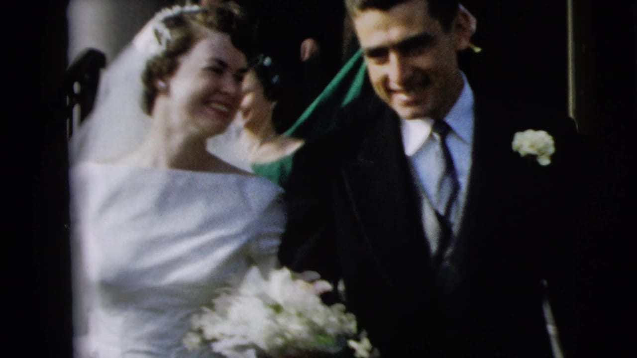 Bride and groom smile while leaving a wedding ceremony with guests close behind.