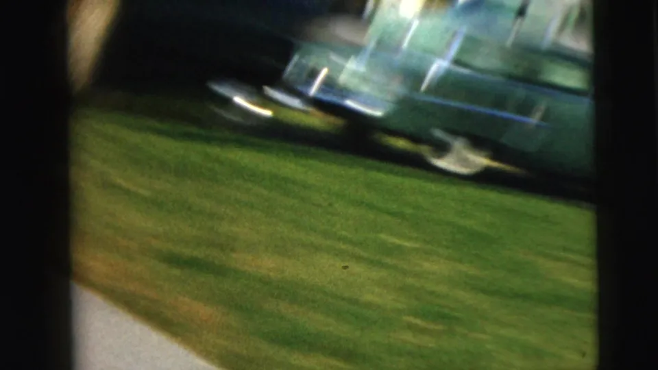 The clip ends with a blurred moving view of a grassy roadside, sidewalk, and parked car in the Camden street setting.