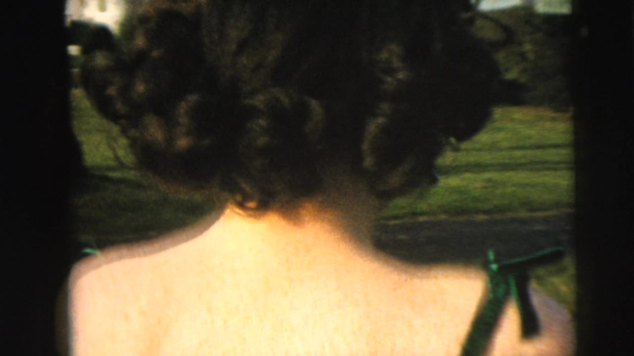 Woman in a shiny green dress seen from behind in an outdoor Camden residential setting in 1962.