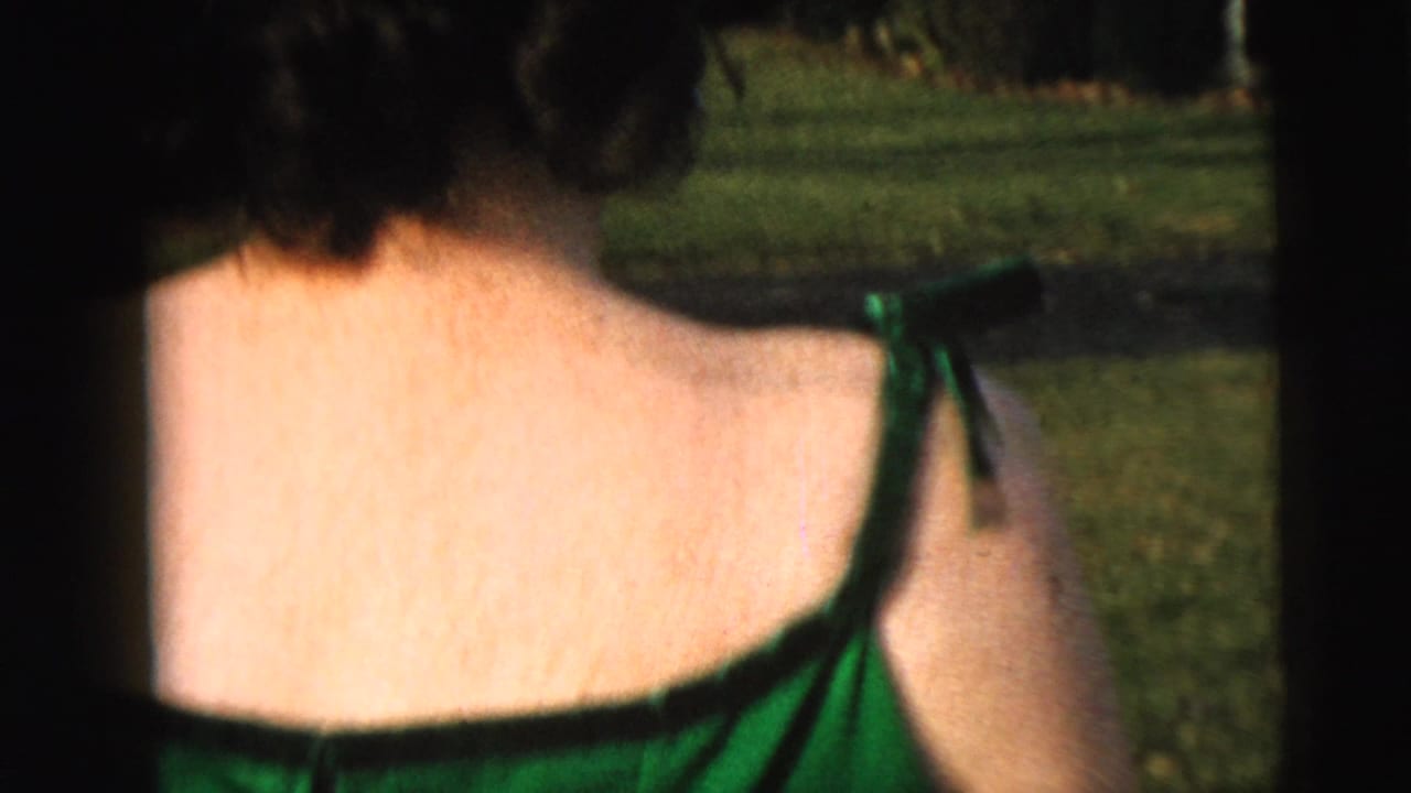 Close view of a woman in a green dress outdoors near a lawn.