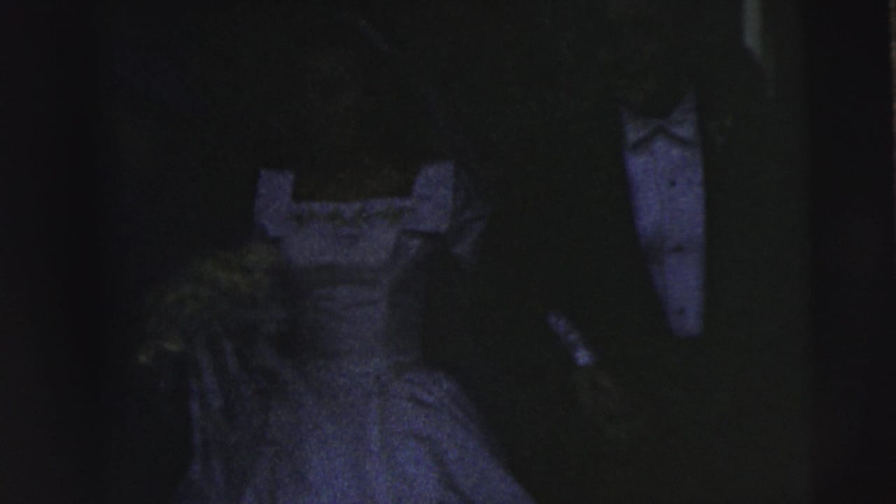 Low-light 1962 Camden wedding frame showing a bride in a light gown beside a groom in a dark tuxedo, with details partly obscured by shadow.