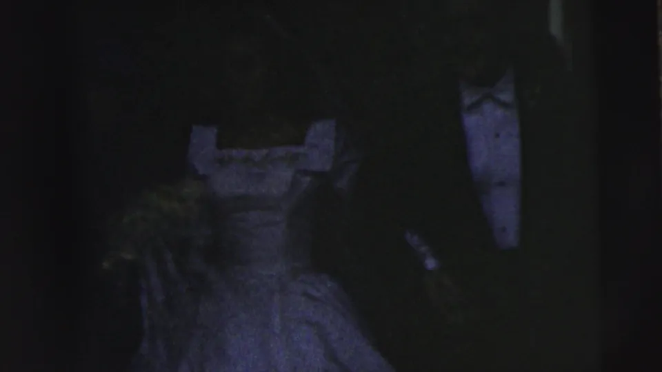 Low-light 1962 Camden wedding frame showing a bride in a light gown beside a groom in a dark tuxedo, with details partly obscured by shadow.