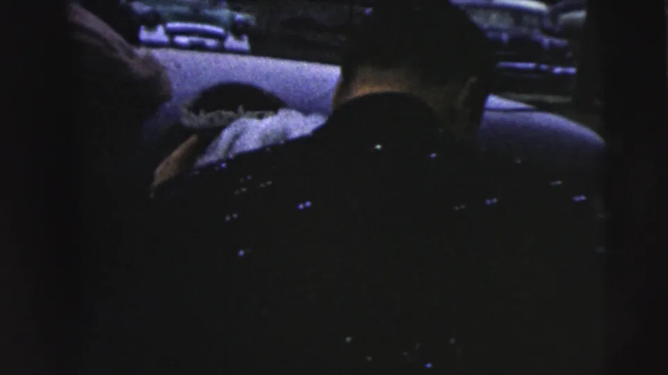 1962 Camden wedding departure frame showing the bride or wedding party inside a dim car interior, with seat backs and a hand visible.