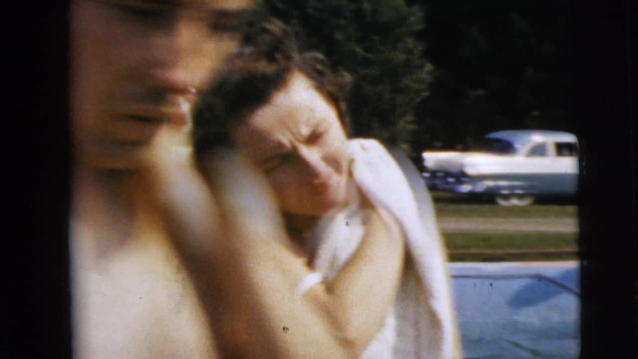 Blurred adults near a pool with a light-colored car parked in the background.