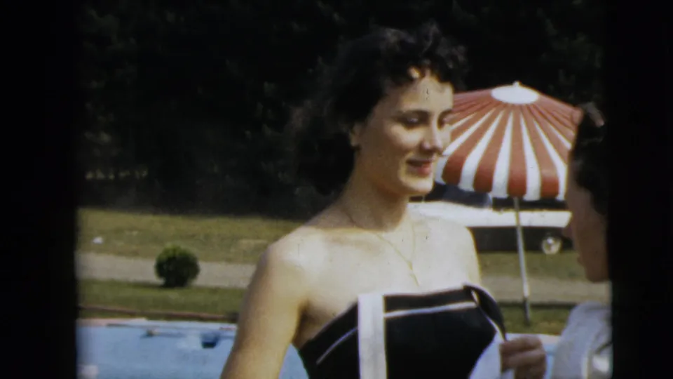 The woman stands by the pool in Camden, New Jersey, facing a partially visible person beside a red and white striped umbrella.