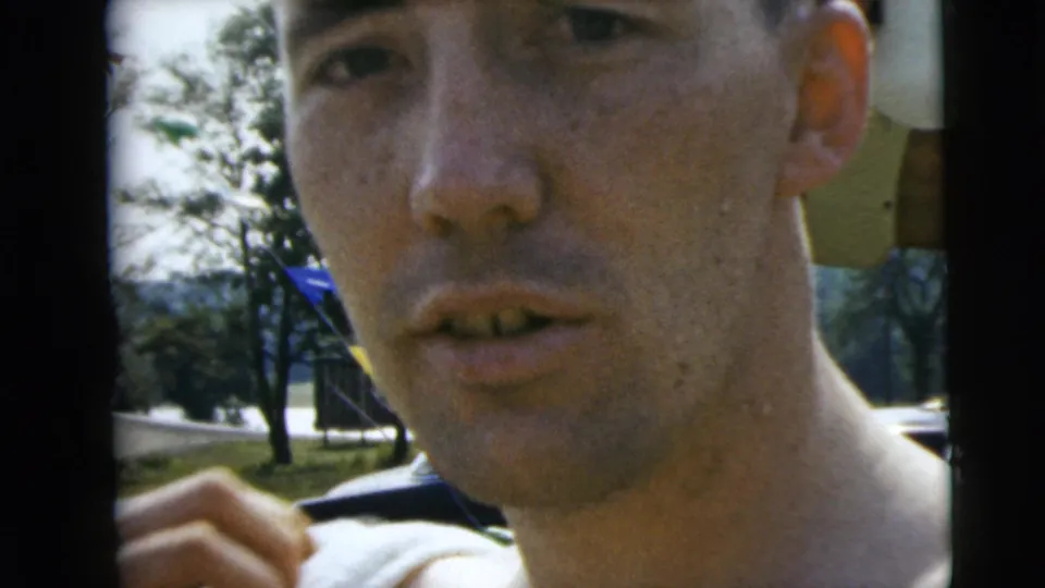 Close-up from the Camden 1962 pool scene showing a man facing the camera, with trees, lawn, and poolside objects behind him.