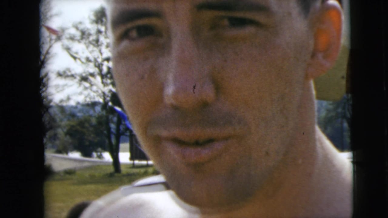 Close-up of a man outdoors near trees and water, cropped tightly at the face and shoulders.