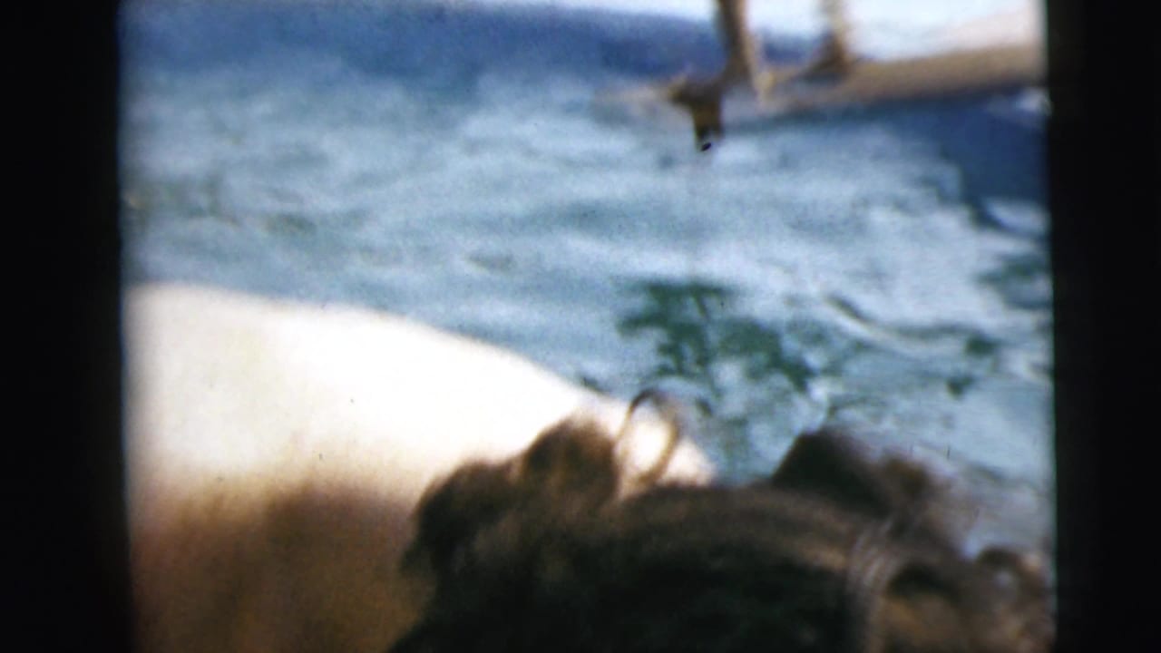 Cropped view of a person bending near pool water, with bright water filling the background.