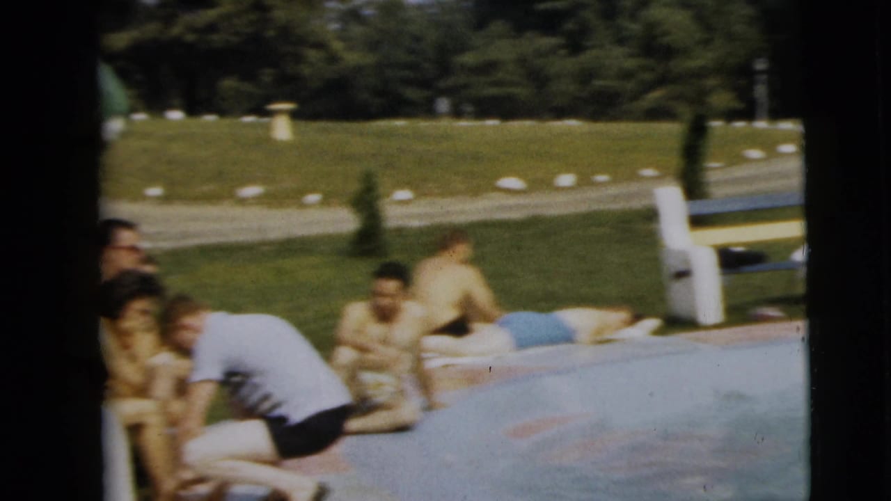 Poolside gathering in Camden, New Jersey, with several people in period swimwear sitting or reclining beside the water.