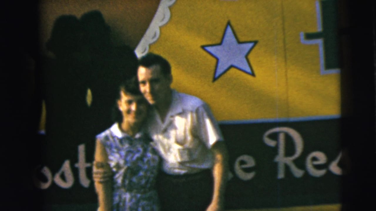 A smiling couple poses together in front of a yellow-and-black sign with a star graphic in Camden, New Jersey, according to the 1962 clip metadata.