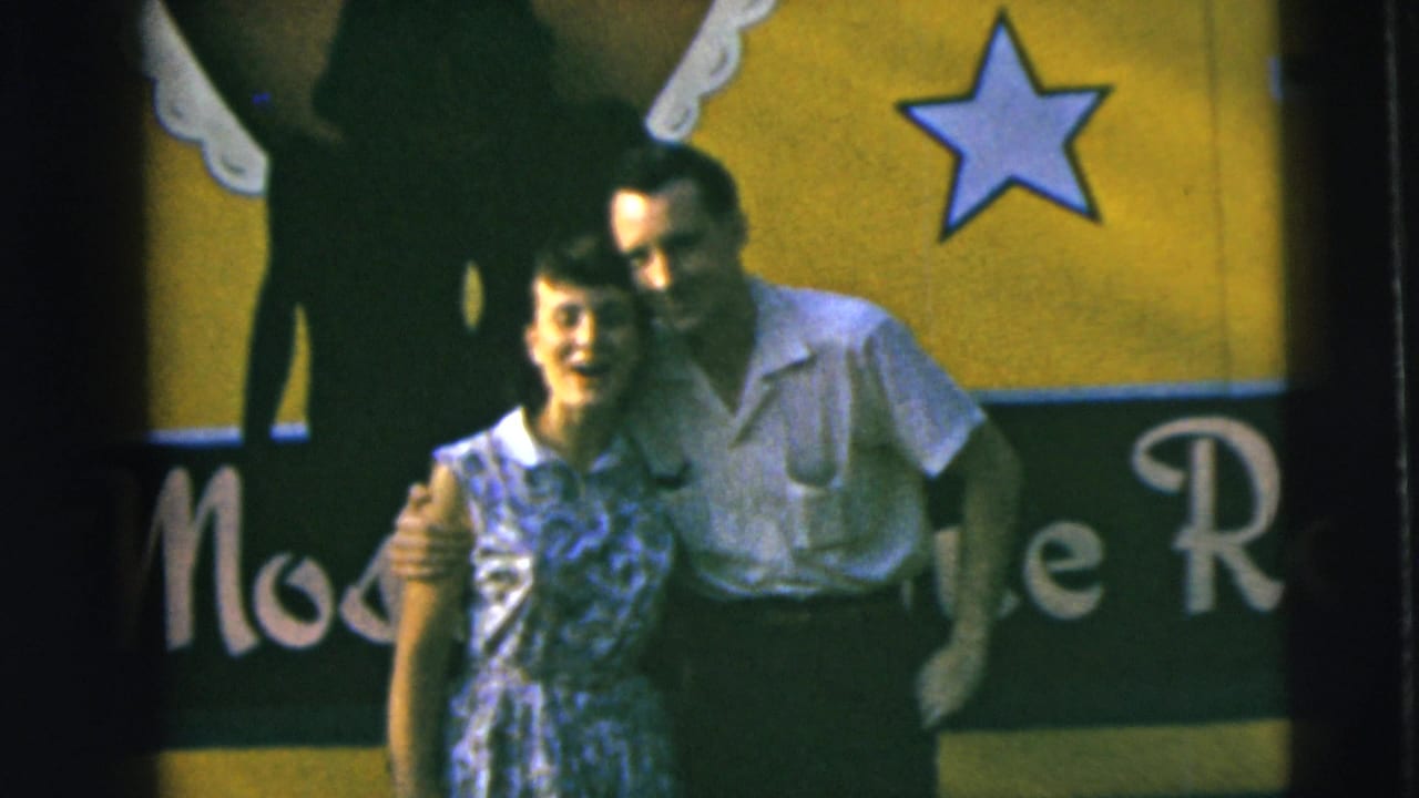 Smiling couple poses in front of a yellow and green sign with a star graphic.