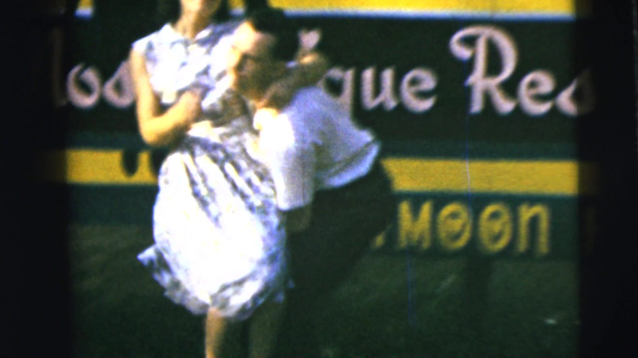 Woman in a patterned dress being lifted in front of a green and yellow sign.