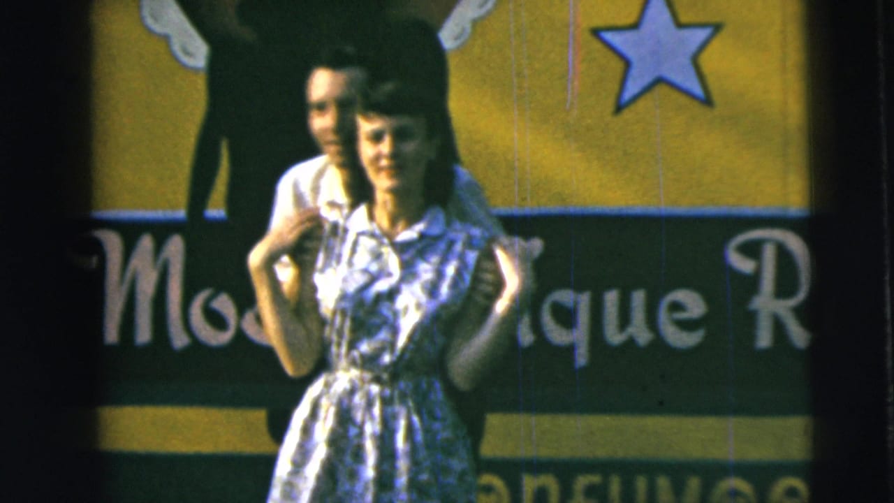Young couple posing closely in front of a colorful painted sign with a star.