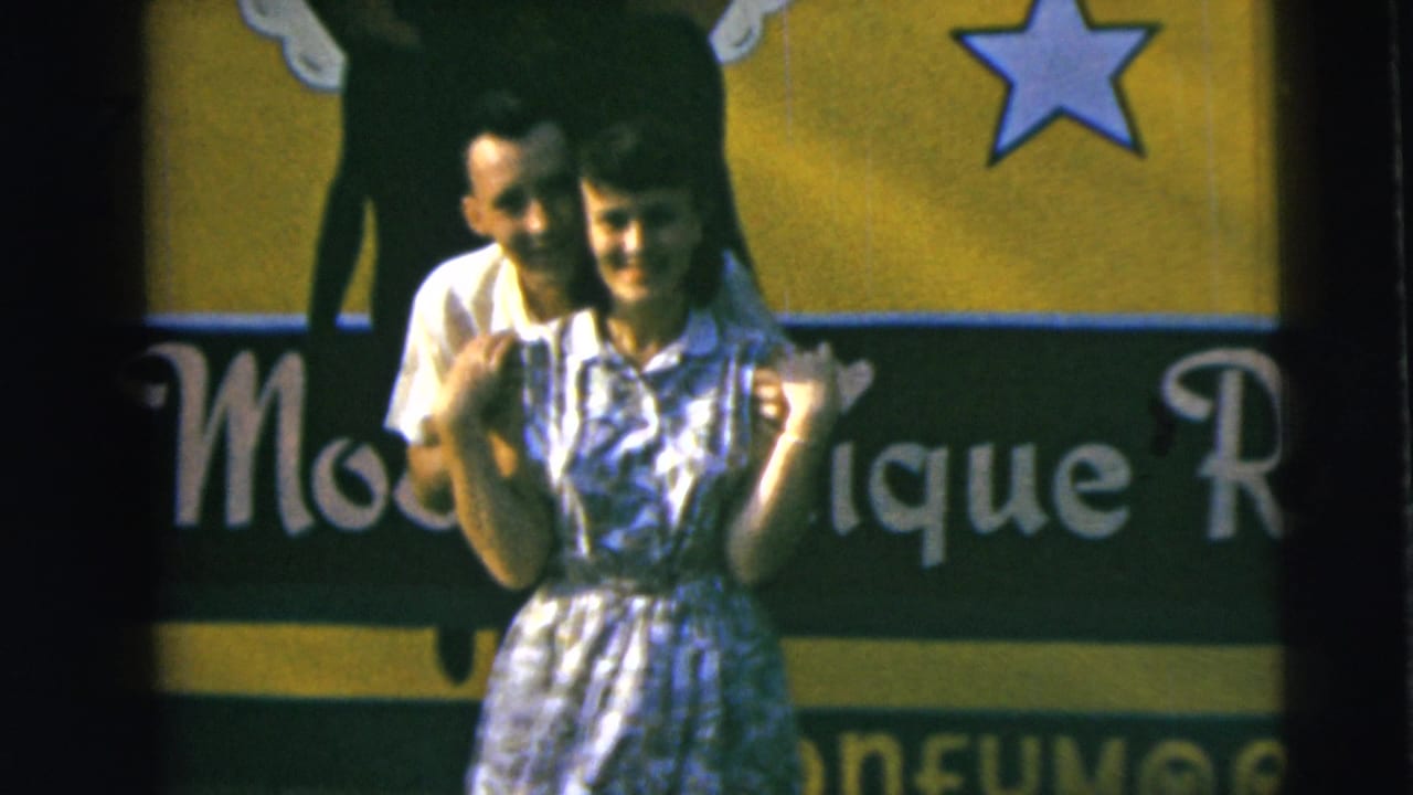 The couple remains close and smiling before the colorful sign, with partial lettering and a star visible in the 1962 Camden footage.