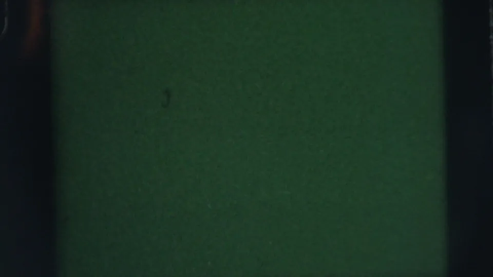 Dark green 8mm leader-like frame with grain, dust specks, and heavy black film borders.