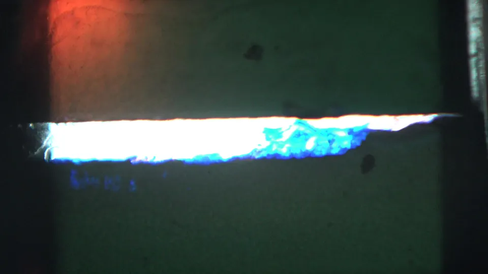 Green-tinted 8mm leader-like frame with a bright horizontal light leak and red-orange flare near the top.