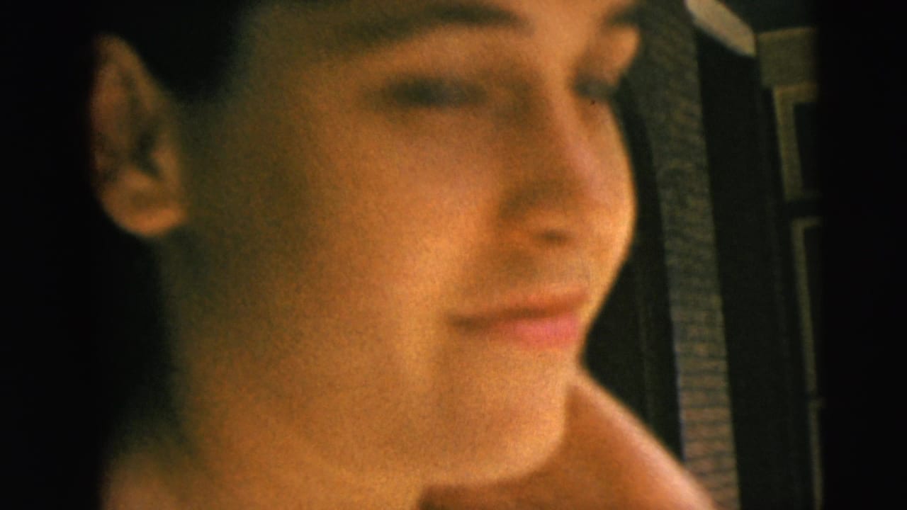 Close view of a woman beside a porch doorway with another seated woman in the background.