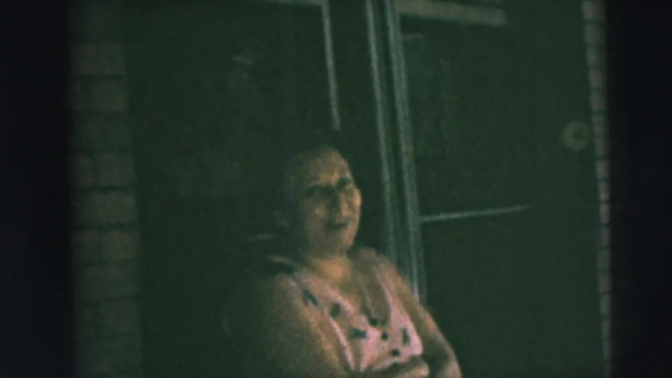 A woman on a Camden residential porch in 1962 appears to smile or laugh as the home-movie camera holds on her.