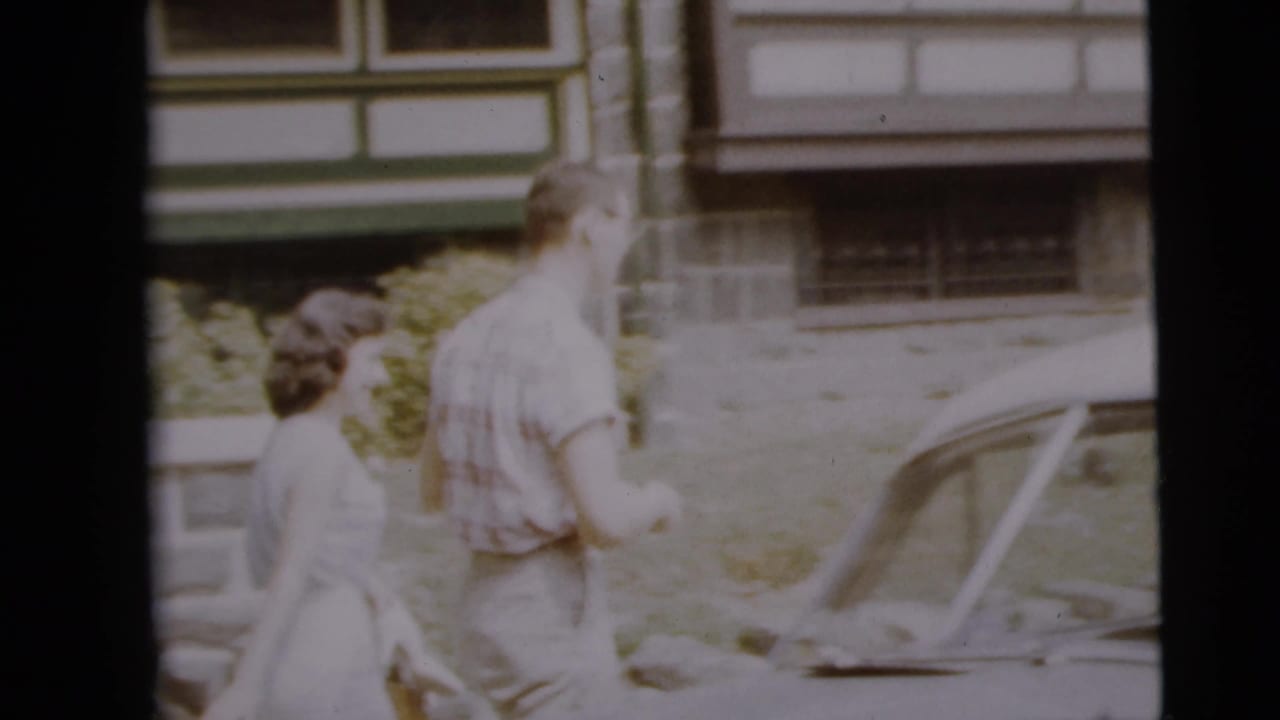 The couple walks toward a vintage parked car in the Camden residential scene.