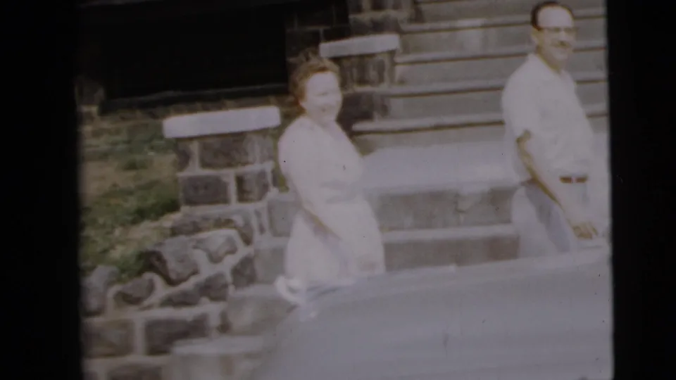 The young couple is seen near the parked car outside the Camden house, with the woman facing toward the camera.