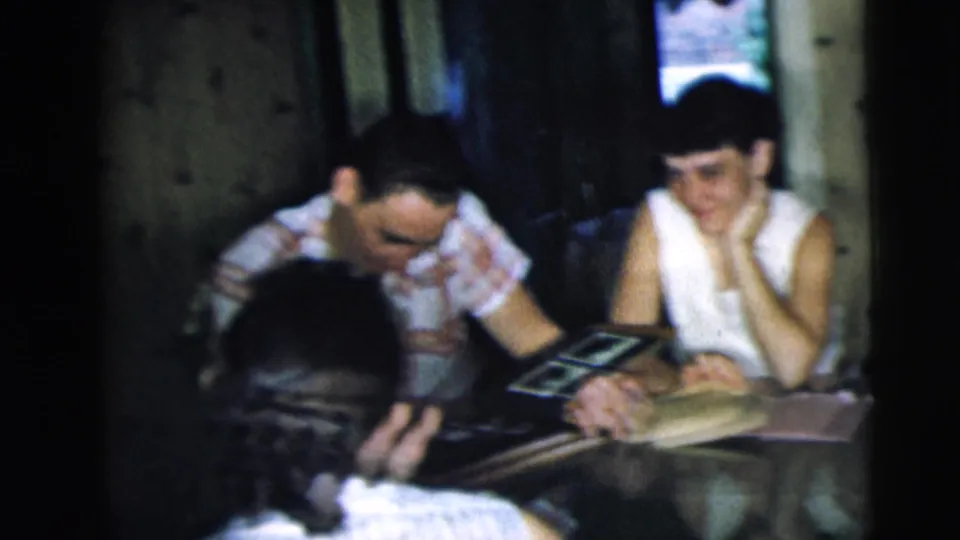 Adults in a Camden, New Jersey interior sit at a table with a photo album, smiling and leaning into the conversation.