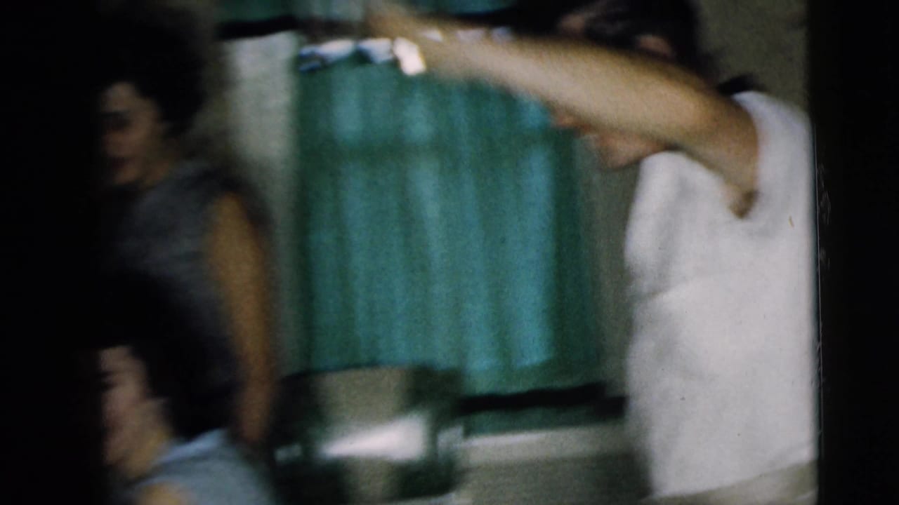 Blurred indoor scene with several adults moving near curtains in a dim room.