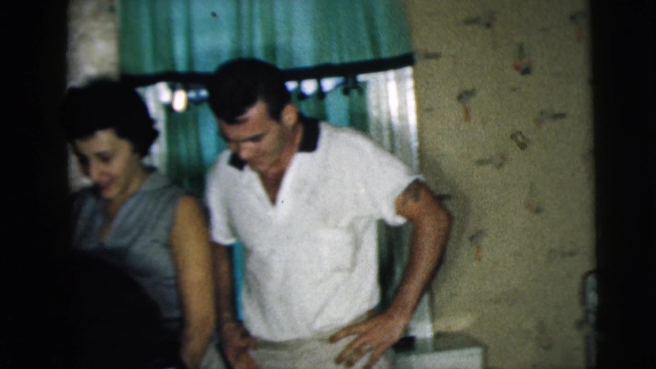 A woman and man stand near seated friends in a dim interior with green curtains.