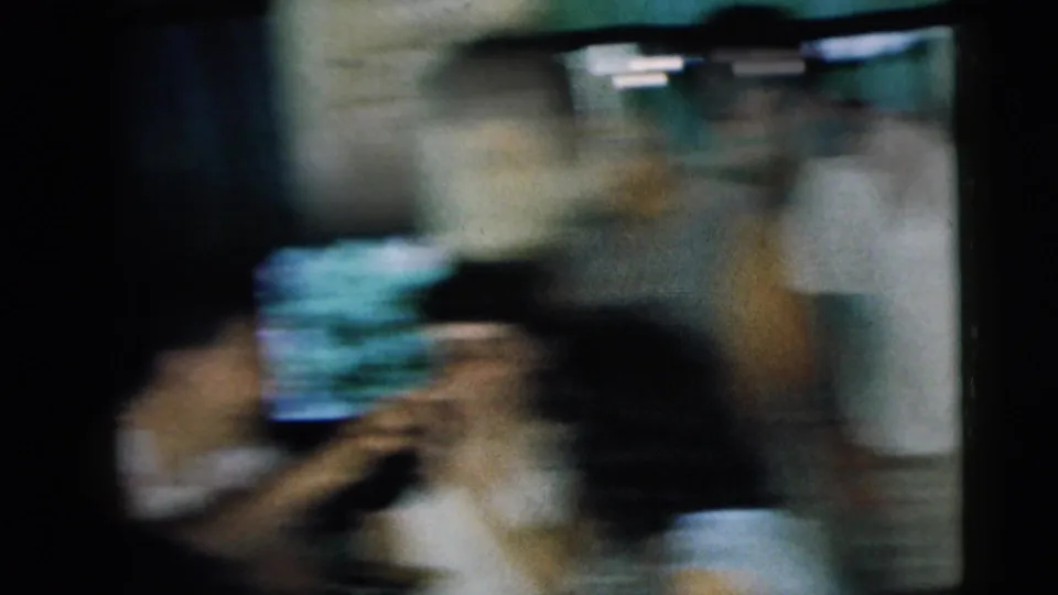 The final 1962 home-movie frame becomes heavily blurred as the handheld camera moves across the indoor gathering.