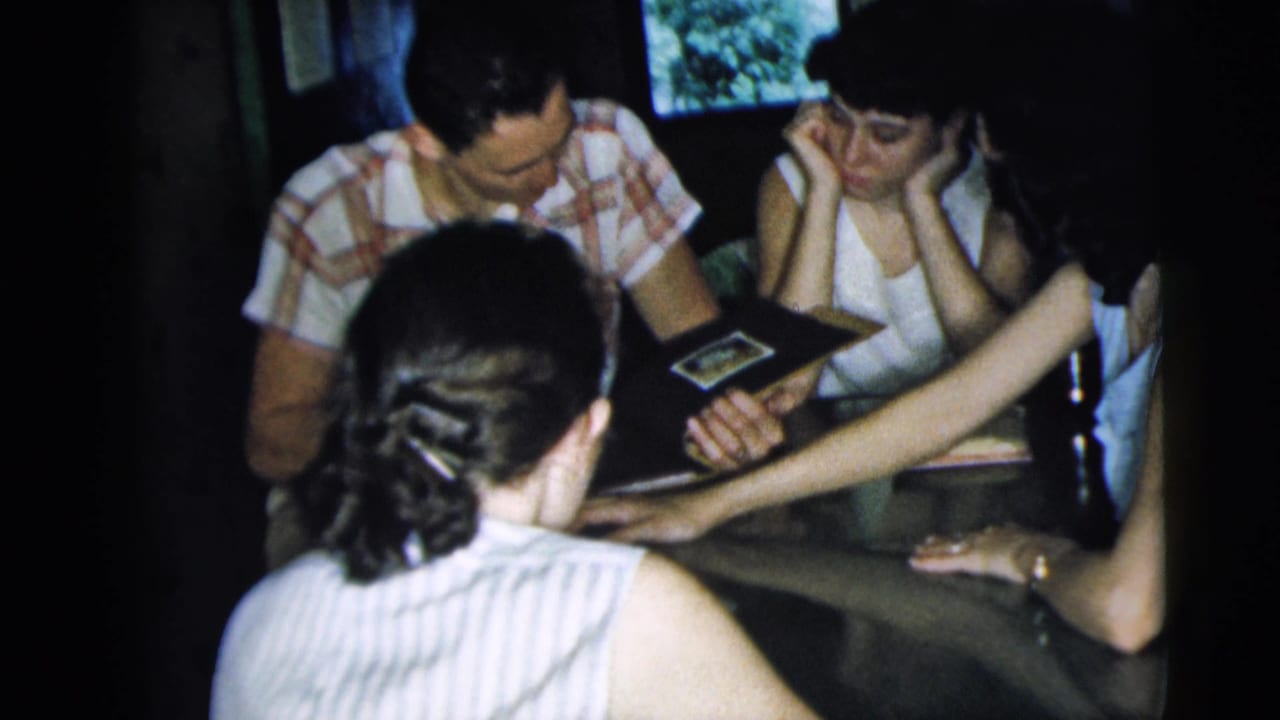 A group at a table studies a photo album while one person reaches across.
