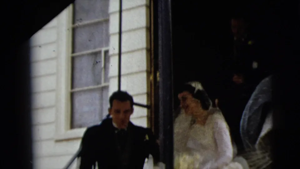 The bride and groom descend the church steps during the 1962 Camden wedding, with a window and siding behind them.