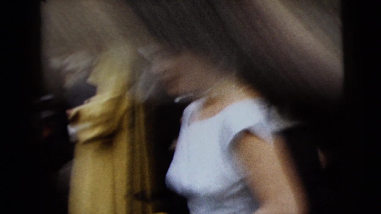 Blurred bride in a light gown moves past wedding guests.