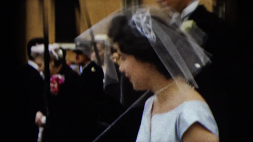 Bride in veil is seen in profile as photographers and formally dressed guests gather behind her in Camden wedding footage.