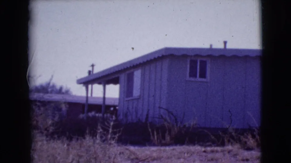 Cottonwood, Arizona ranch house exterior on 8mm film, framed by dark gate edges with dry brush in the foreground.