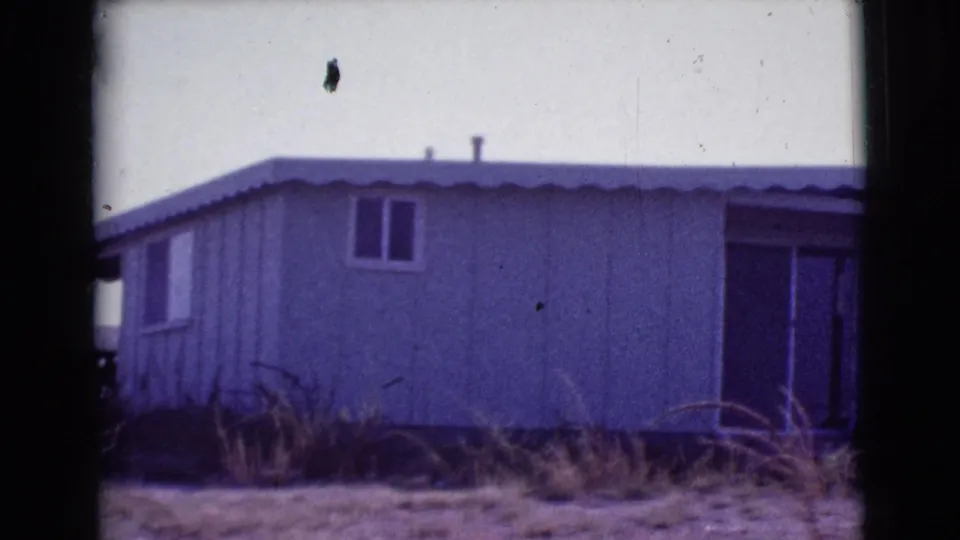 1964 Cottonwood, Arizona 8mm frame showing more of the home exterior, including a small window and darker doorway area at right.