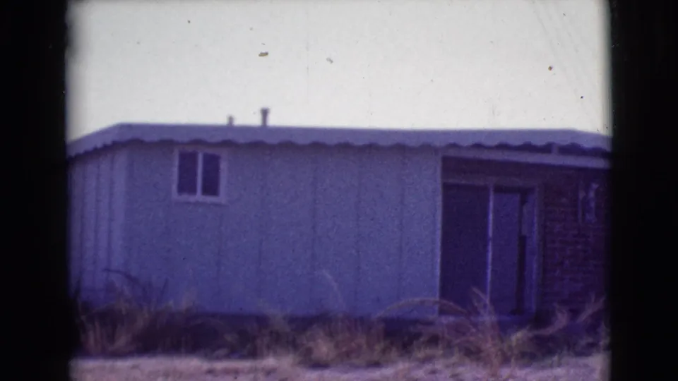 1964 Cottonwood, Arizona frame showing the right end of the mobile or prefab home, with a doorway area and brick section visible.