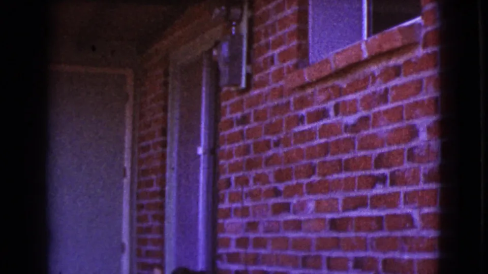 1964 Cottonwood, Arizona exterior frame with a white door, brick facade, adjacent window, and vertical pipe in purple-shifted 8mm color.