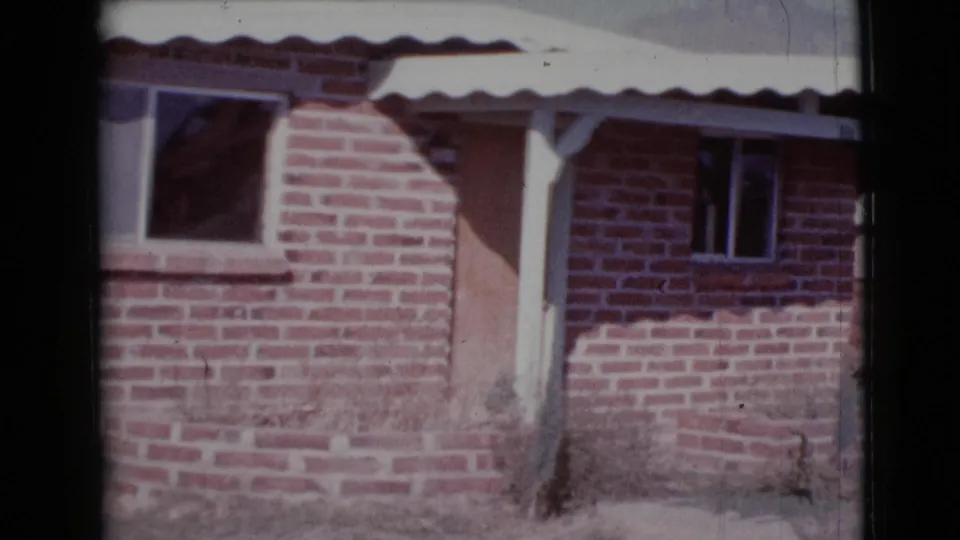 1964 Cottonwood, Arizona frame of the brick house exterior, with a white awning over the porch, boarded door, and dark window openings.