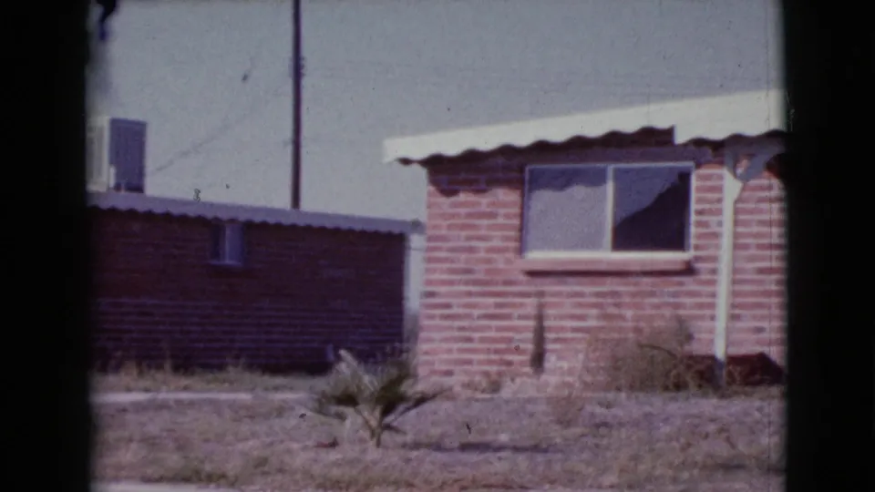1964 Cottonwood, Arizona frame with a brick home, low boundary wall, window unit, and small desert-yard plant.